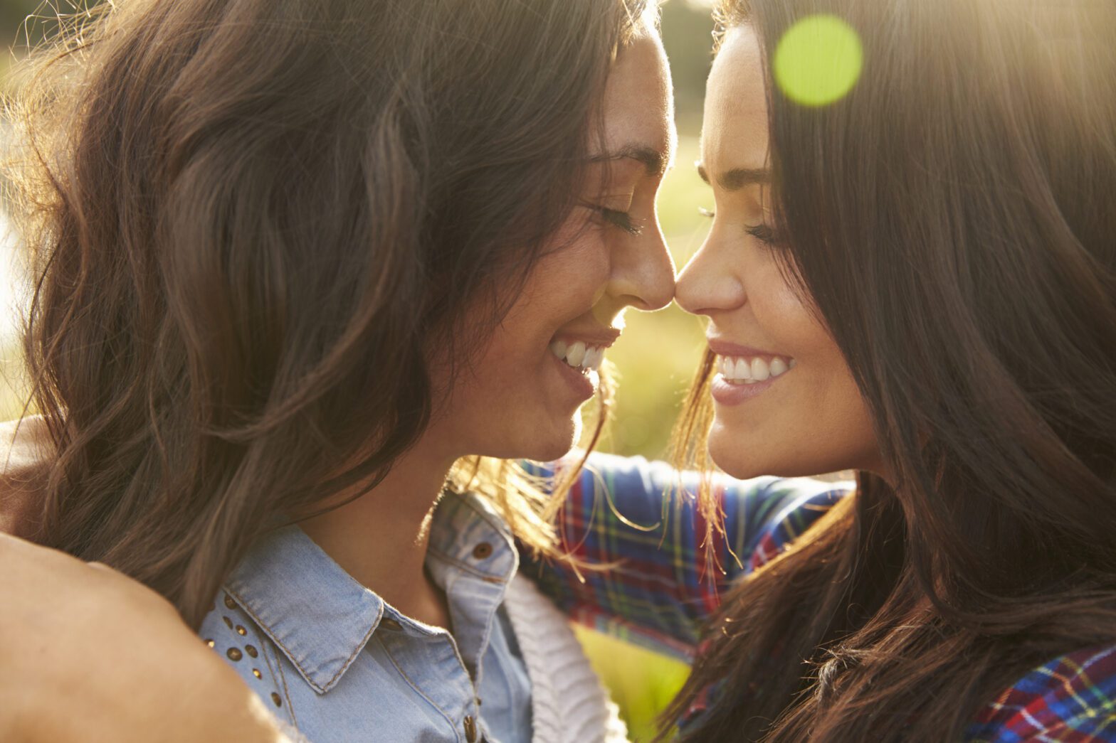 Lesbian couple embrace touching noses, eyes closed, close up